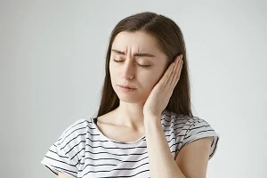 девушка держится за ухо